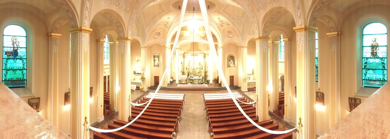 Wnętrze kościoła parafialnego: nawę w kierunku ołtarza, witraże i ławy.
